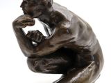 bronze statue of a man sitting on his knees with his hand on his chin