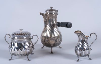 trois théières en argent et deux tasses en argent posées sur une table