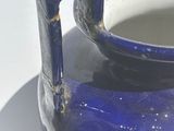 a blue vase sitting on a plate on a table