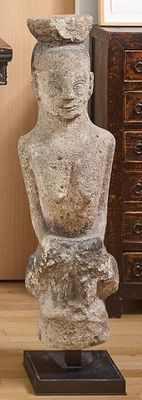 une statue représentant un homme assis sur une table, à côté d'une commode