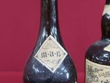 two bottles of wine sitting next to each other on a red surface