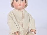a baby doll sitting on the ground wearing a sweater and hat
