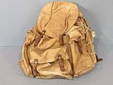 un sac à dos beige posé par terre