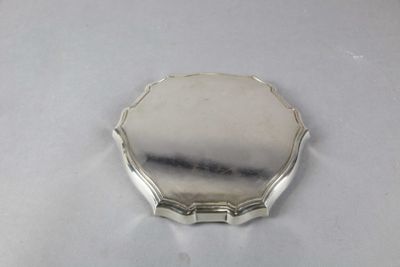 une image représentant une petite assiette en argent posée sur une surface blanche