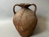 un vase brun posé sur une table à fond blanc