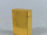 a gold plated cigarette case on a white surface