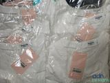 a pile of white shirts wrapped in plastic bags