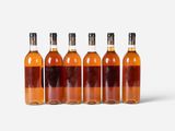 six bottles of whiskey lined up in a row on a white surface