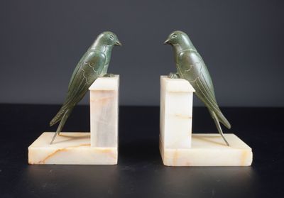 une paire d'oiseaux verts posés sur des serre-livres en marbre, sur fond noir