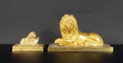 une paire de statues de lions en or posées sur des socles en marbre, sur un fond noir