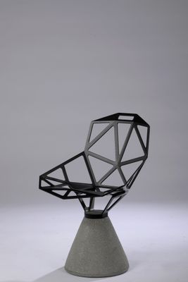 La chaise est en béton et présente un design géométrique.