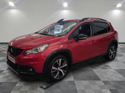 une voiture rouge est garée dans une pièce au sol en damier