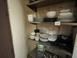 many plates and pans on the shelves in the kitchen