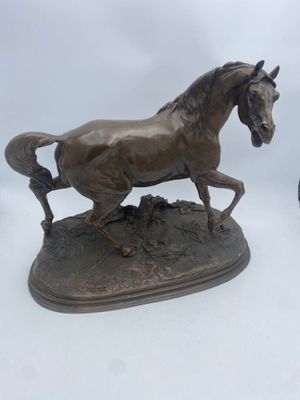 two bronze statues of a horse and a bird on a white surface