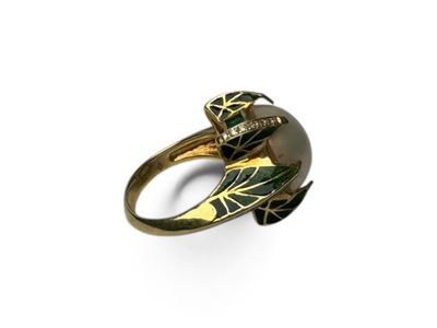 un gros plan d'une bague en or ornée d'une feuille verte