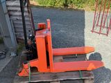 a fork lifter sitting on a pallet in front of a building