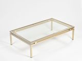 une table basse en verre et en laiton sur fond blanc