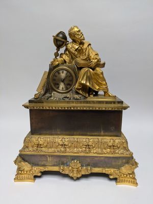 a gold statue of a woman sitting on top of a clock