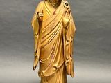 statue of a person with a robe and shoes on a wooden base