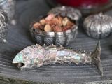 a silver fish sitting on top of a table next to other silver objects