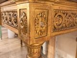 a gold table with a marble top sitting on a wooden floor