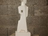 a white sculpture sitting on a wooden stool in front of a brick wall