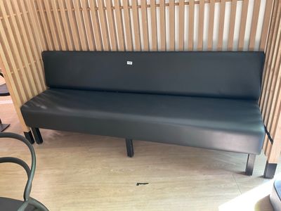 a black leather bench in a room with a wooden wall behind it