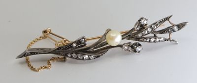 a silver and gold brooch with pearls on it