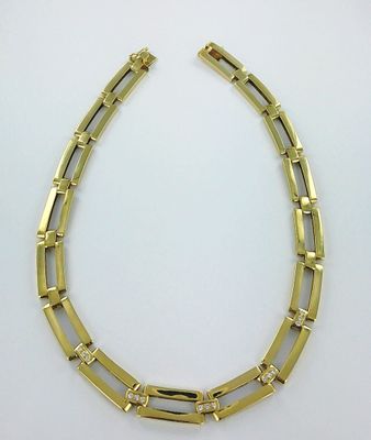 un collier en or composé de maillons carrés et de diamants sur fond blanc
