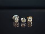trois boucles d'oreilles en or et diamants posées sur un fond noir