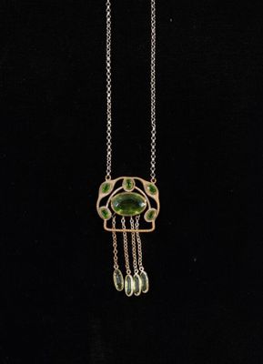 a gold and green necklace with a bird design on it