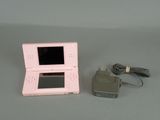 a pink nintendo wii game console next to a charger