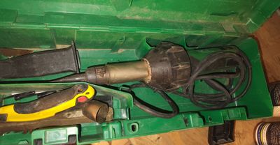 une boîte verte contenant des outils, posée sur un plancher en bois