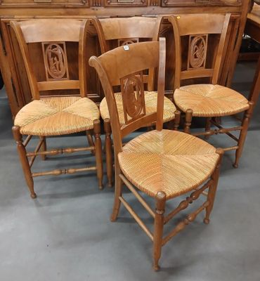 Quatre chaises en bois sont alignées en rangée dans une pièce.