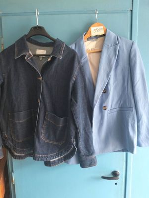 deux vestes accrochées à une porte bleue devant une porte bleue
