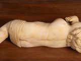 a statue of a baby laying down on a wooden table