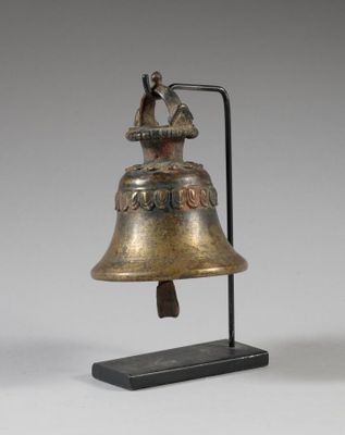 une vieille cloche posée sur un socle, sur laquelle est perché un oiseau