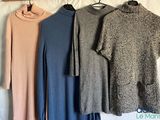 three sweaters hanging on a clothes rack on a bed