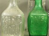 two green glass bottles sitting next to each other on a table