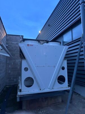 un climatiseur installé sur le toit, à côté d'un immeuble