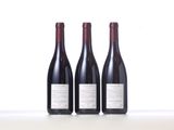 three bottles of red wine are lined up on a table