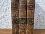 three old books sitting on top of a wooden table