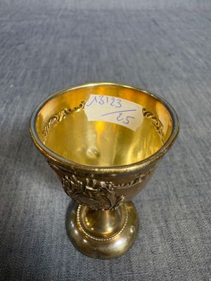 une tasse plaquée or, sur laquelle est collé un autocollant, posée sur une table