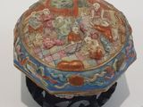 une petite boîte décorative posée sur un socle, sur une surface blanche