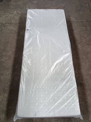 un matelas emballé dans du plastique, posé à même le sol