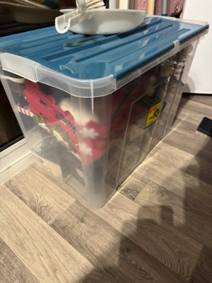 une boîte en plastique posée par terre, avec un gobelet dessus