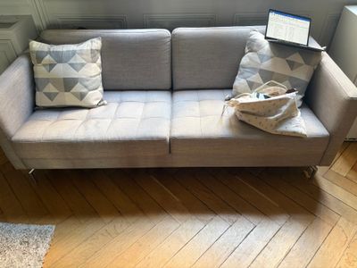 a couch with two pillows and a laptop on top of it