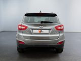 the rear end of a silver car parked in a white room