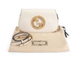 a white purse with a gold ring on the handle and a belt