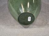 a green vase with a tag on it sitting on a table